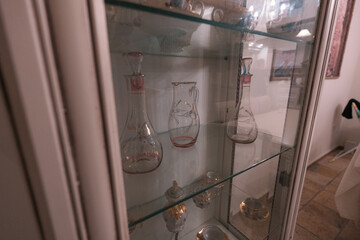 Empty glass containers with crockery on shelf in cabinet