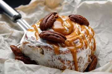 Cinnabon bun with cinnamon, cream, nougat and nuts. Close-up