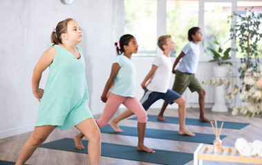 Fototapeta premium Active children doing stretching workout for body flexibility in yoga studio