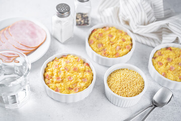 Cheesy millet with ham slices in a baking bowl