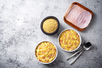 Cheesy millet with ham slices in a baking bowl