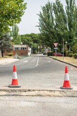 Traffic cones in front of a ditch to signal asphalt conditioning works