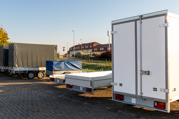 Many different types small passenger car cargo freight trailers parked in row at sale or rental...