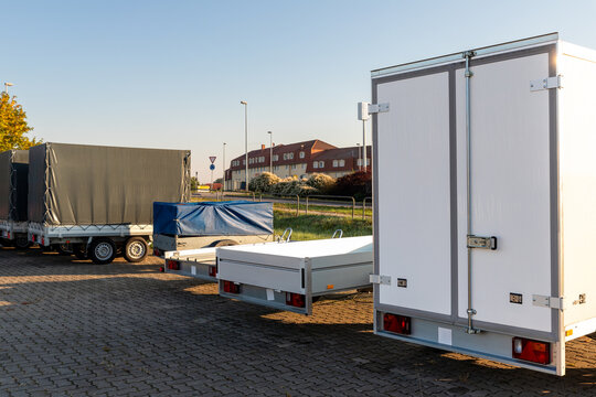 Many different types small passenger car cargo freight trailers parked in row at sale or rental site. Business and home transportation delivery. Service production and maintenance equipment