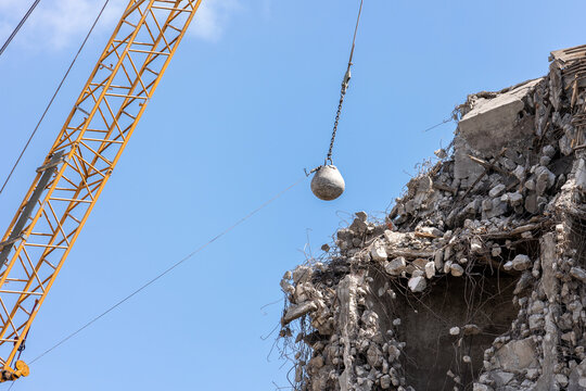 Heavy wrecking ball crane demolishing old building against blue sky in Magdeburg Germany. Building dismantling and construction waste disposal recycling service