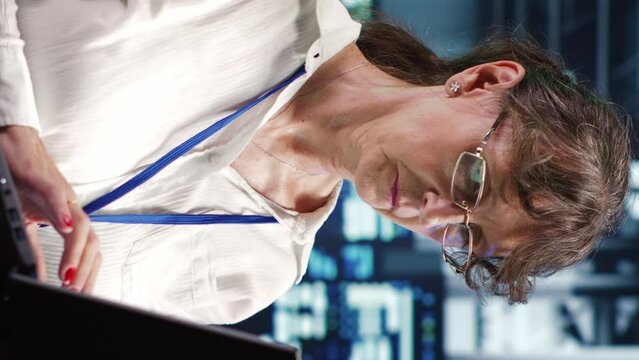 Vertical video Knowledgeable supervisor looking around advanced data center, preparing to start comission on damaged high tech blade servers in order to ensure optimal operations