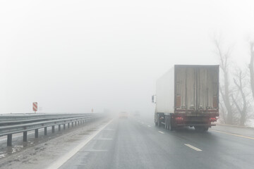 Driver POV on traffic on blue foggy misty rainy slush highway intercity road with low poor...