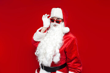 santa claus in glasses looks at the camera and suspects on colored background, puzzled man in santa costume