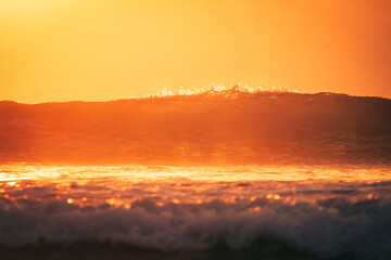 As the sun dips towards the horizon, a wave surges forward, capturing the sunset's radiant glow. It's a face-to-face encounter with the ocean's heart, illuminated by the day's final rays.
