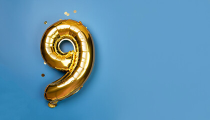Banner with number 9 golden balloon with copy space. Nine years anniversary celebration concept on a blue background.