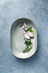 Herbs, challots and garlic cloves in a ceramic dish. Top view. Copy space