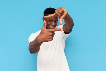 african american man in white t-shirt shows frame and square with his hands on blue isolated...