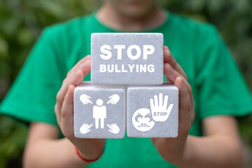 Schoolgirl holding white plastic foam blocks with inscription: STOP BULLYING. Bullying and violence at school concept. Social problems of humanity. Stop bullying. Cyber-bullying, online violence.