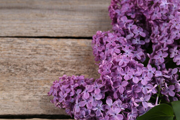Beautiful lilac flowers on wooden table, closeup. Space for text