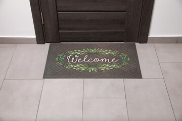 Beautiful doormat with word Welcome on floor near entrance