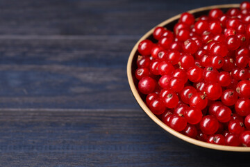Ripe red currants in bowl on wooden rustic table, closeup. Space for text