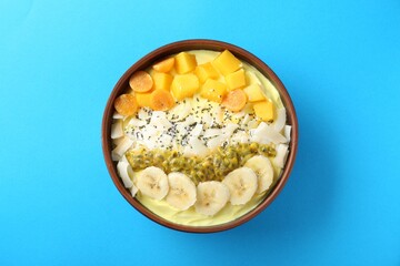 Tasty smoothie bowl with fresh fruits on light blue background, top view