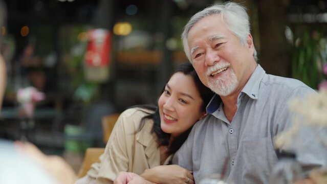 4K Happy Asian couple and elderly father having lunch eating meal together at cafe restaurant on summer holiday vacation. Family relationship, father's day and old senior people health care concept.