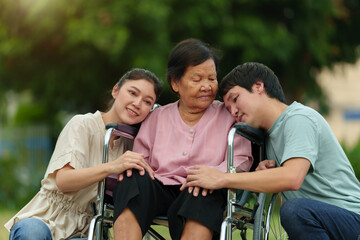 happy grandson and granddaughter with senior woman in wheelchair at park