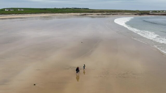 Aerial video of a family having fun on the Beautiful Tullagh Strands Sandy Beach on the Atlantic Ocean in County Donegal Ireland 08-08-23