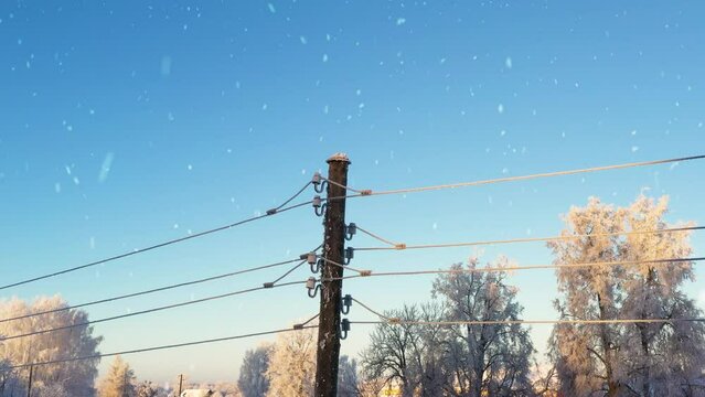Local electric pole covered with ice and snow. Concept of electricty and blackouts problem during winter snowstroms in rural areas