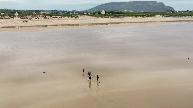 Aerial video of a family having fun on the Beautiful Tullagh Strands Sandy Beach on the Atlantic Ocean in County Donegal Ireland 08-08-23