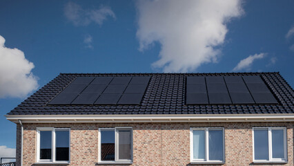 Newly build houses with solar panels attached on the roof against a sunny sky Close up of new building with black solar panels. Zonnepanelen, Zonne energie, Translation: Solar panel, , Sun Energy