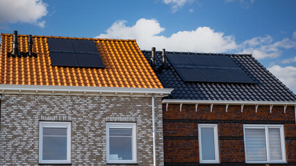 Newly build houses with solar panels attached on the roof against a sunny sky. black solar panels on a roof