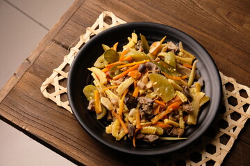 Sautéed baby corn, carrots, chicken gizzard liver, chilies, green tomatoes on a black plate on...