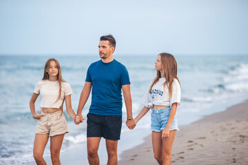 Portrait of father with his adorable daughters on the beach during their summer vacation - 634914782