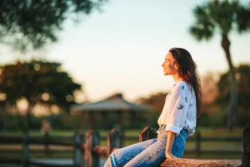 Portrait of happy young woman outdoor in the park at sunset - 634915321