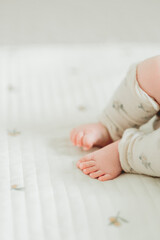 春の午後、布団で眠る日本人の赤ちゃんのレッグウォーマーを着けた両足 - obrazy, fototapety, plakaty