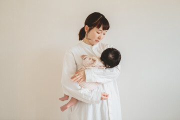 春の朝、屋内の幼い女の子を抱っこして立つ日本人の茶髪の女性