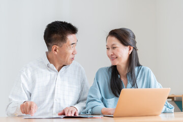 Obraz premium 旅行パンフレットを見て予約をするシニア夫婦