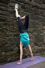 Athletic woman doing a handstand against a wall.