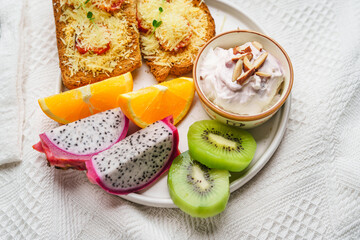 Breakfast toast with cheese and tomatoes, fruit, yogurt, coffee.