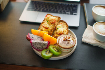Breakfast toast with cheese and tomatoes, fruit, yogurt, coffee.