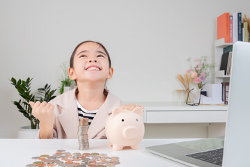 Asian little cute girl wearing a cream suit analyzing coins finance and investment