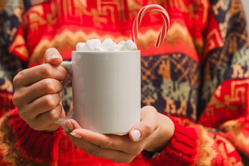 Woman in red sweater holding white cup with hot chocolate close-up. Christmas mug mock-up
