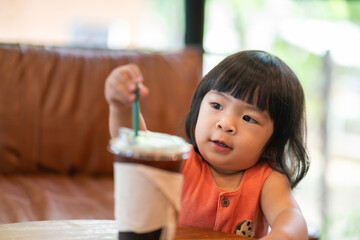 Portrait photo of white little girl with black hair is wearing orange suit in cutety action. People portrait photo with facing focus.