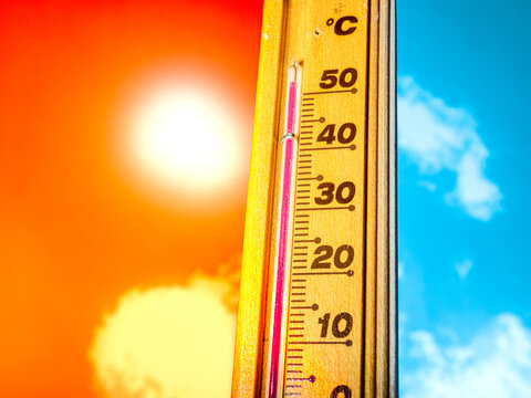 A hot summer day, with the thermometer showing a high heatwave temperature of 50 degrees Celsius. A red alarm gives a warning of the extreme weather conditions caused by global climate change.