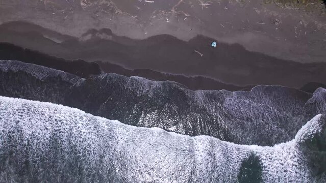 Aerial view of the waves of the sea reaching the beach on the coast of Quepos, Costa Rica