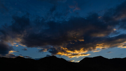 A dramatic view of silhouette of mountains with sunrays falling through clouds