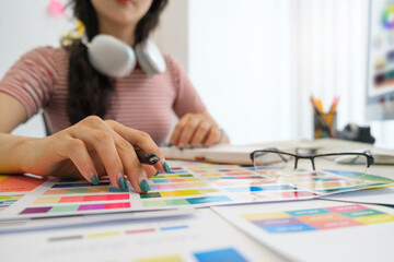 Interior designer working with color samples, choosing colorful paper charts at desk.