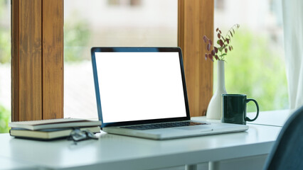 Home office desk with computer laptop, coffee cup and houseplant on wood table.