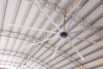 HVLS big fan on ceiling under the old metal curve roof structure of industrial building, low angle...