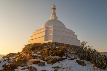 White Buddhist stupa on small sacred hill in lake Baikal, Russia during sunset.