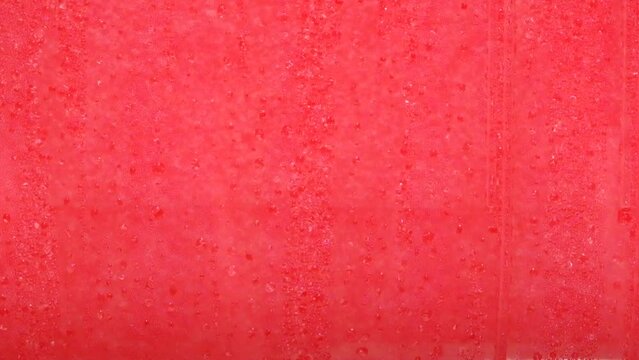 Drops of condensation on the ice cream tank. Ice cold sorbet machine mixing fruit juice. Freezing slush spinning around, summer treat. Crushed iced coloured with fruit flavor sweeteners 