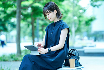 屋外でタブレットPCを操作する若い女性