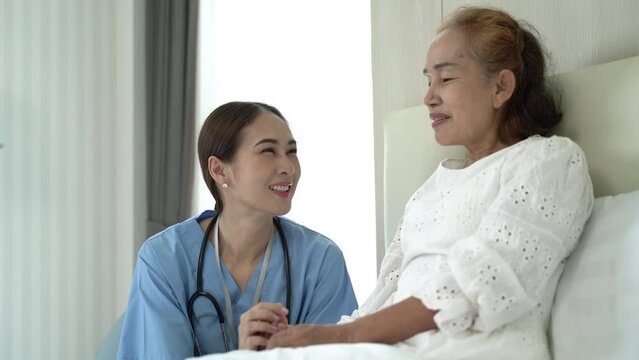 Take care senior lady patient on the bed talking to caring female nurse at home. Concept of wellness consultation, caregiver, elderly healthcare and homeopathic doctor.